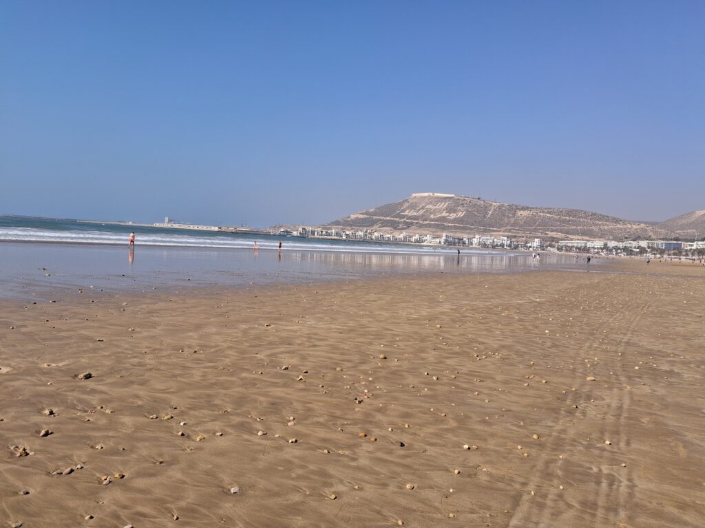 The long, sandy beach of Agadir with sun loungers and the ocean.